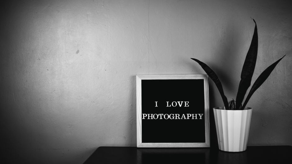 Monochrome image featuring a message board with 'I LOVE PHOTOGRAPHY' and a plant.